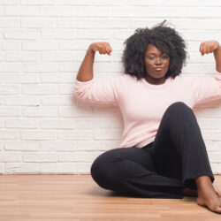 Young African American woman sits and flexes arms after conquering urge incontinence | CU Urogynecology | Denver, CO